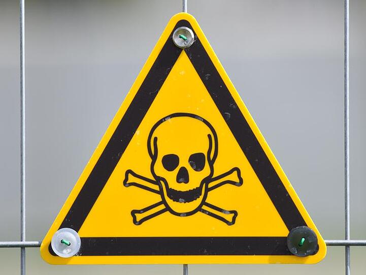 Ein Warnschild mit einen Totenkopf-Symbol hängt an einem Bauzaun.