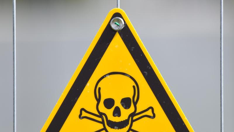 Ein Warnschild mit einen Totenkopf-Symbol hängt an einem Bauzaun. Ein Warnschild mit einen Totenkopf-Symbol hängt an einem Bauzaun.