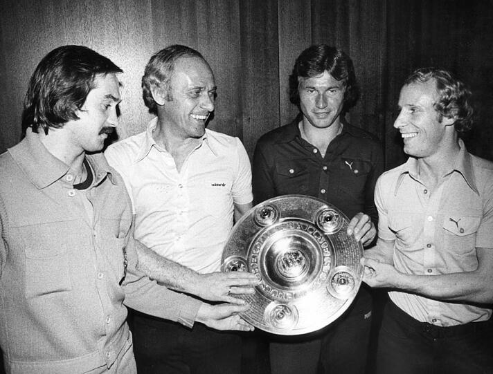 Als Trainer von Mönchengladbach: Udo Lattek (2.v.l.) und seine Spieler Uli Stielike (l), Jupp Heynckes (2.v.r.) und Berti Vogts (r) posieren am 21.5.1971 in einem Münchner Hotel mit der eroberten Meisterschale.