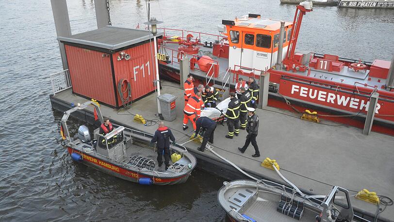 Eine Leiche wird von einem Boot der Feuerwehr Hamburg auf einen Steg im Hafen getragen. Eine Leiche wird von einem Boot der Feuerwehr Hamburg auf einen Steg im Hafen getragen.