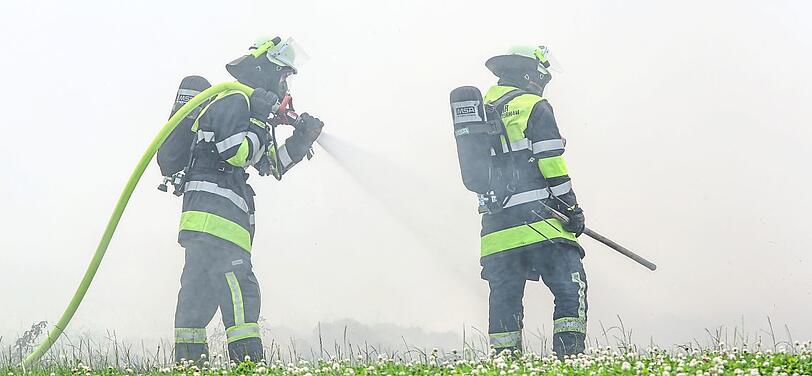 Zwei Feuerwehrleute löschen das brennende Stroh.