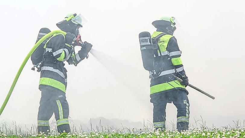 Zwei Feuerwehrleute löschen das brennende Stroh. Zwei Feuerwehrleute löschen das brennende Stroh.
