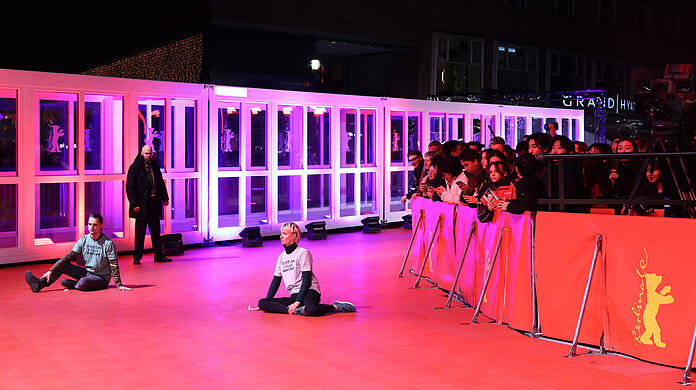 Zwei junge Menschen haben sich auf dem roten Teppich der Berlinale festgeklebt