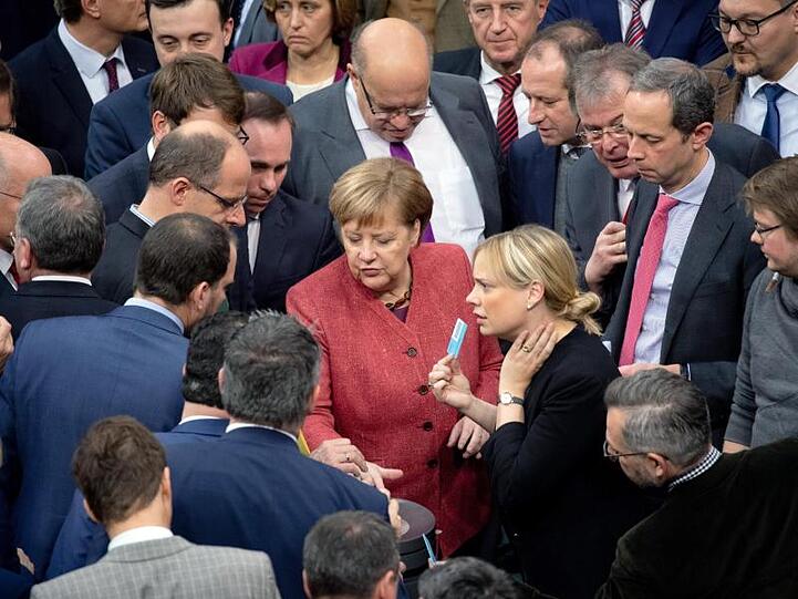 Bundeskanzlerin Angela Merkel (M) gibt bei der namentlichen Abstimmung über den UN-Migrationspakt ihre Stimmkarte ab.