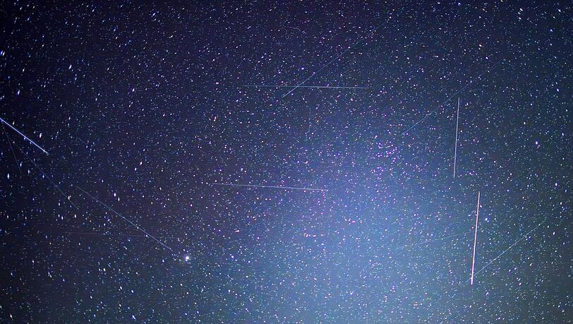 Erdnahe Satelliten sind auf Langzeitbelichtungen als Lichtspuren zu erkennen. Das bayerische Start-Up Mynaric baut Laserfunkterminals f&uuml;r Satelliten und ist nun von einem US-Konzern &uuml;bernommen worden. (Symbolbild)