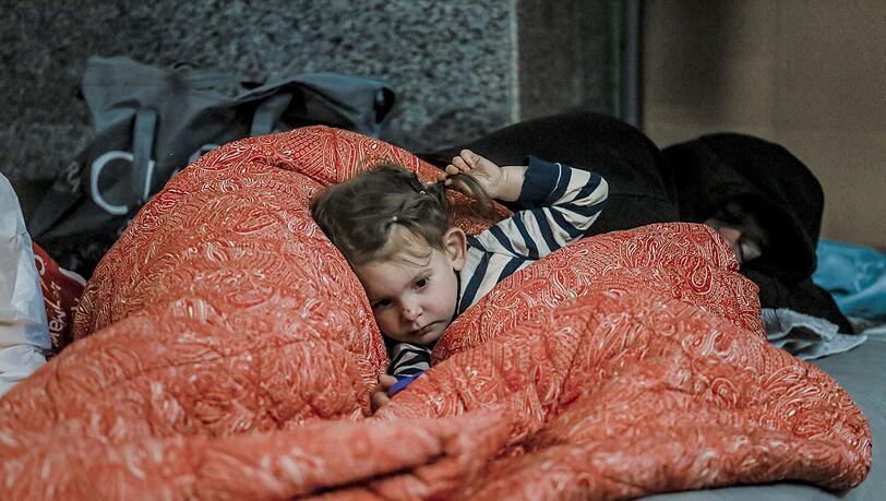 Ein kleines Mädchen liegt in einer Metrostation in Charkiw unter einer Decke. Die ostukrainische Millionenstadt war in der Vergangenheit Ziel russischer Raketen. Ein kleines Mädchen liegt in einer Metrostation in Charkiw unter einer Decke. Die ostukrainische Millionenstadt war in der Vergangenheit Ziel russischer Raketen.