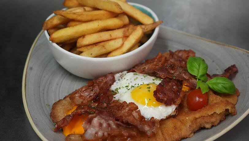 Bei Platt und Belegt in der Schwanthalerhöhe stehen belegte Schnitzel auf der Speisekarte, wie hier mit Cheddar-Käse, Bacon und Ei.
