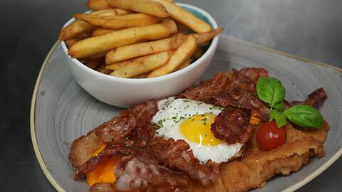 Bei Platt und Belegt in der Schwanthalerhöhe stehen belegte Schnitzel auf der Speisekarte, wie hier mit Cheddar-Käse, Bacon und Ei.