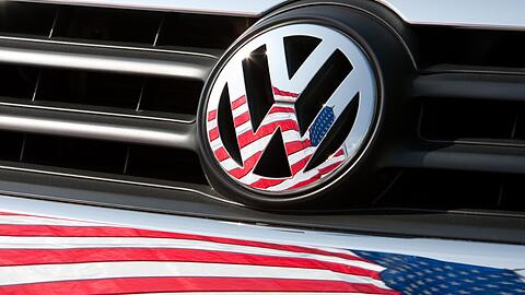 Die US-Fahne spiegelt sich in Logo und Kühlergrill eines Volkswagen-Fahrzeugs.