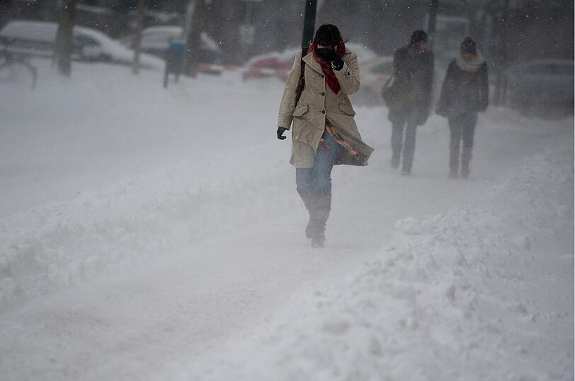 Eine Frau kämpft sich durch das Schneegestöber in München.