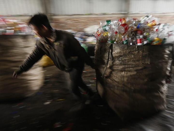 In einer Sammel- und Sortieranlage in Peking zieht ein Arbeiter einen Sack voller gebrauchter Plastikflaschen.