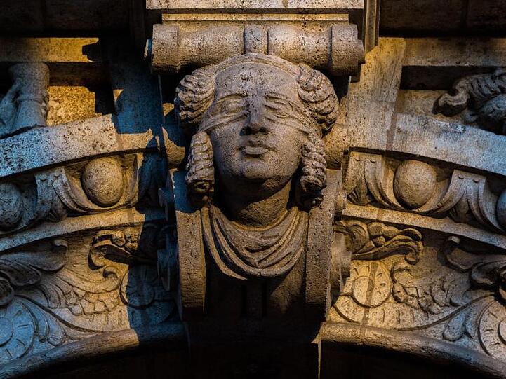 Die morgendliche Sonne scheint auf die Skulptur der Justitia ein einem Gerichtsgebäude. Foto: Nicolas Armer/Archiv