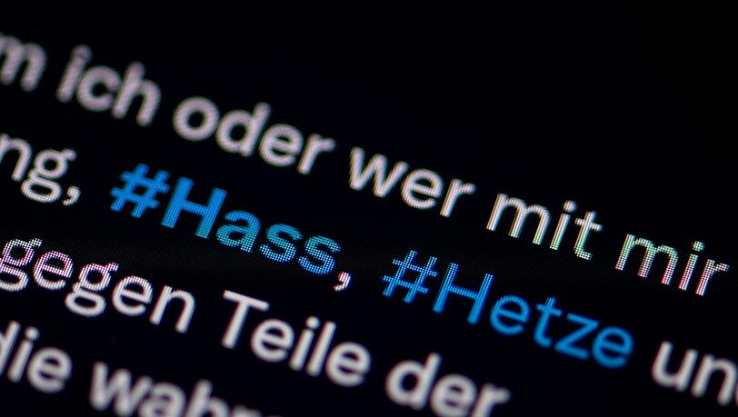 Auf dem Bildschirm eines Smartphones sieht man die Hashtags Hass und Hetze in einem Twitter-Post.