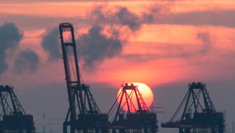 Hinter den Containerbrücken eines Terminals im Hamburger Hafen geht die Sonne unter. Hinter den Containerbrücken eines Terminals im Hamburger Hafen geht die Sonne unter.