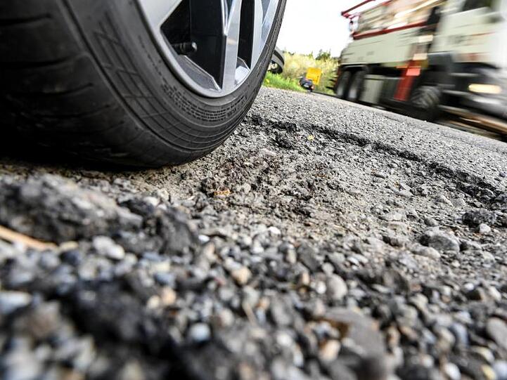 Ein Auto steht neben einer Bundesstraße in einem Schlagloch. Foto: Felix Kästle/Archivbild