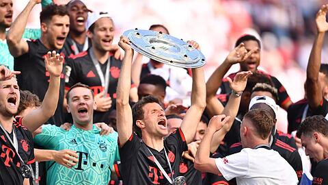 Bayerns Thomas Müller (M) hält die Meisterschale hoch während seine Teamkollegen nach dem Gewinn der 33. deutschen Meisterschaft jubeln.
