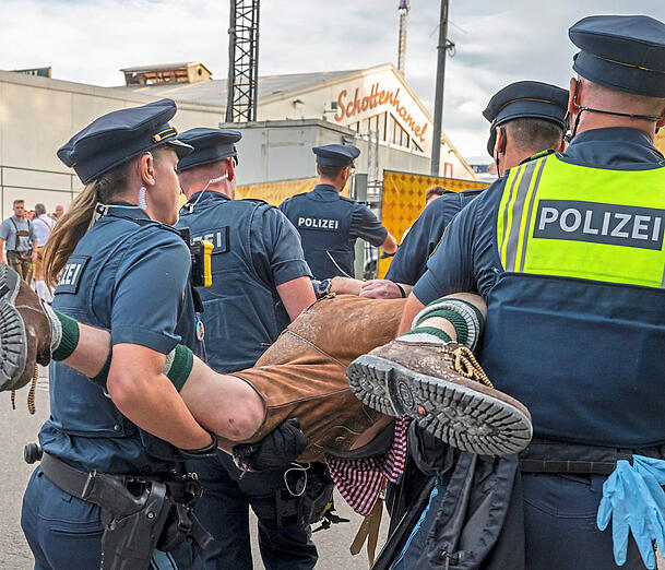 Oktoberfest 2023: Polizeibeamte der Wiesn-Streife tragen einen betrunkenen Randalierer hinter einem Bierzelt weg.  Foto: dpa