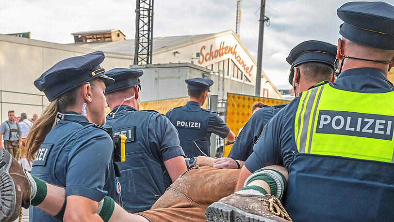 Oktoberfest 2023: Polizeibeamte der Wiesn-Streife tragen einen betrunkenen Randalierer hinter einem Bierzelt weg.