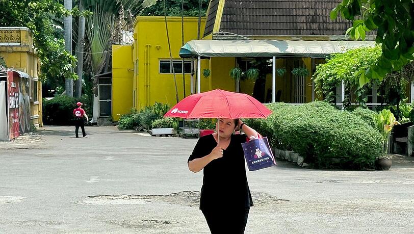 Viele sch&uuml;tzen sich mit Schirmen vor der Sonne.