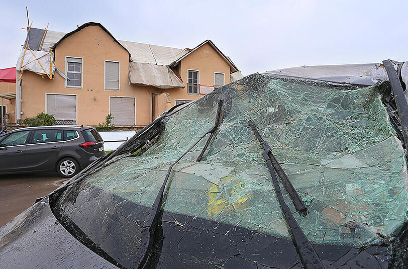 Ein vom Tornado zerstörtes Auto steht in der Gemeinde Affing vor einem beschädigten Wohnhaus.