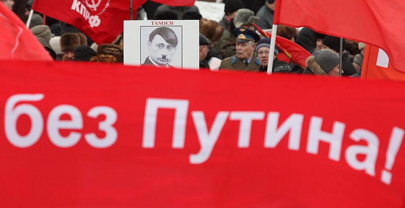 Während der Pro-Putin Demo, versammelten sich Tausende,um gegen den Kremlkandidaten zu protestieren. Anhänger der Oppositionspartei "Kommunistische Partei der Russischen Föderation" (KPRF) hielten Banner mit "Russia - without Putin" hoch oder stellten Putin als Adolf Hitler dar.