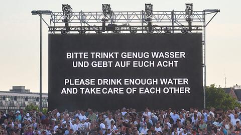 "Bitte trinkt genug Wasser und gebt auf Euch Acht" steht bei hochsommerlichen Temperaturen auf einer Leinwand bei einem Konzert von Techno-Star Paul Kalkbrenner auf dem Heiligengeistfeld in Hamburg.