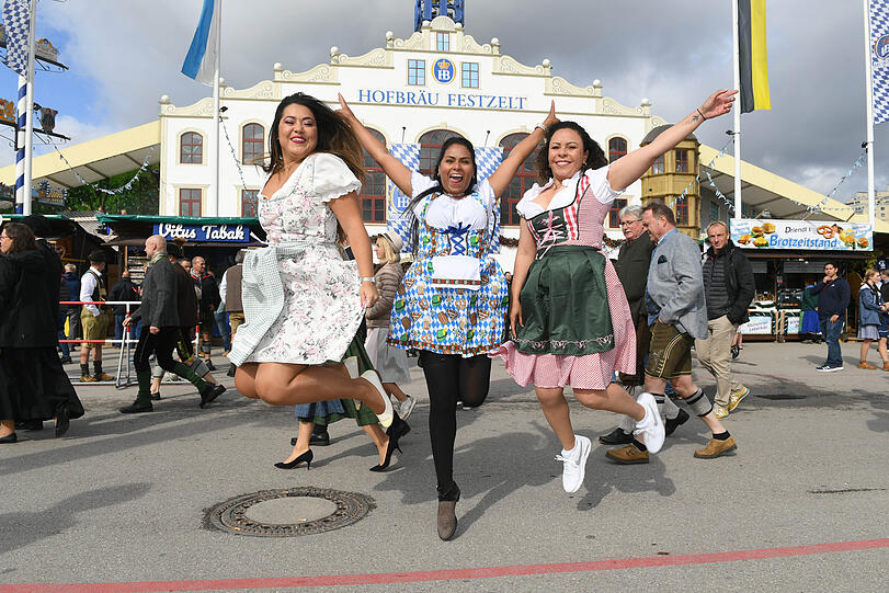 Michelle, (v. l.) Josi und Gessilgug aus Brasilien springen vor dem Einzug der Wiesnwirte auf der Theresienwiese beim Start des 187. Münchner Oktoberfests vor dem Hofbräuzelt in die Höhe