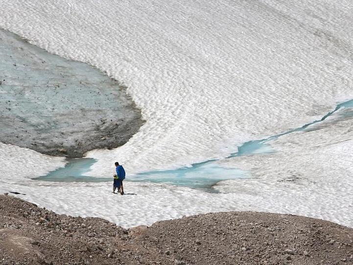 Zwei Wanderer gehen über den Schneeferner-Gletscher auf der Zugspitze. Foto: Stephan Jansen/dpa/Archivbild