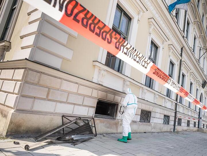 Ein Polizist von der Spurensicherung steht vor einem Kellerfensters des bayerischen Finanzministeriums in der Innenstadt. Foto: Peter Kneffel