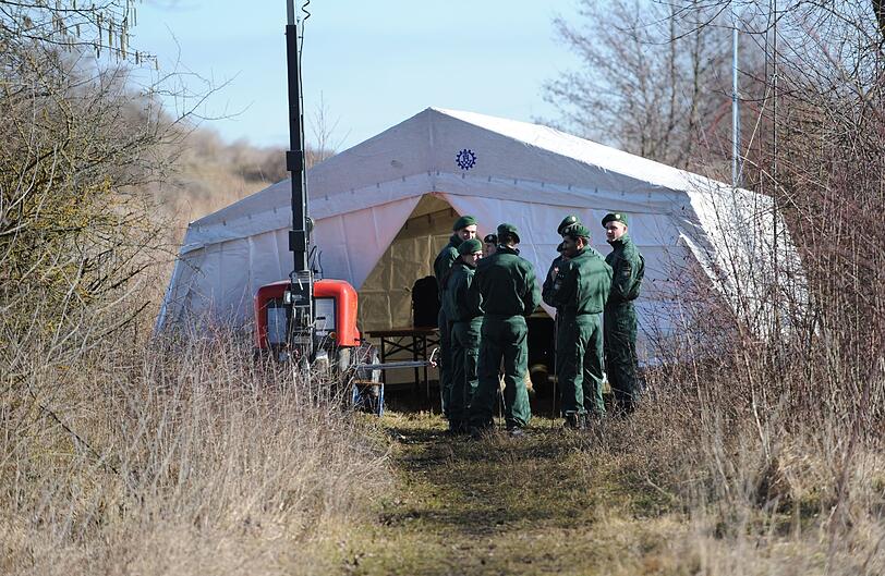 Polizisten stehen am Montag vor einem Zelt der Spurensicherung am Ufer des Rathei-Weihers zwischen Zell und Karlshuld.