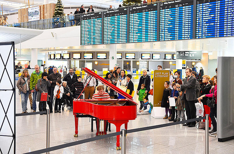 Der rote Steinway-Flügel unter der Anzeigetafel im Terminal 2 des Münchner Flughafens.