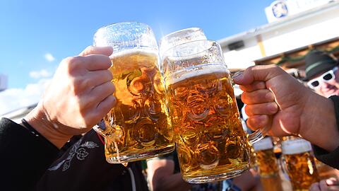 Besucher stoßen auf dem Oktoberfest mit Maßkrügen voller Bier an. (Symbolbild)