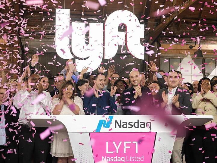 Börsengang geglückt: Die Lyft-Gründer John Zimmer (M. l.) und Logan Green (M. r.) jubeln im Konfetti-Regen vor dem leuchtenden Firmenschriftzug.