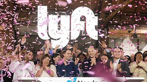 Börsengang geglückt: Die Lyft-Gründer John Zimmer (M. l.) und Logan Green (M. r.) jubeln im Konfetti-Regen vor dem leuchtenden Firmenschriftzug.