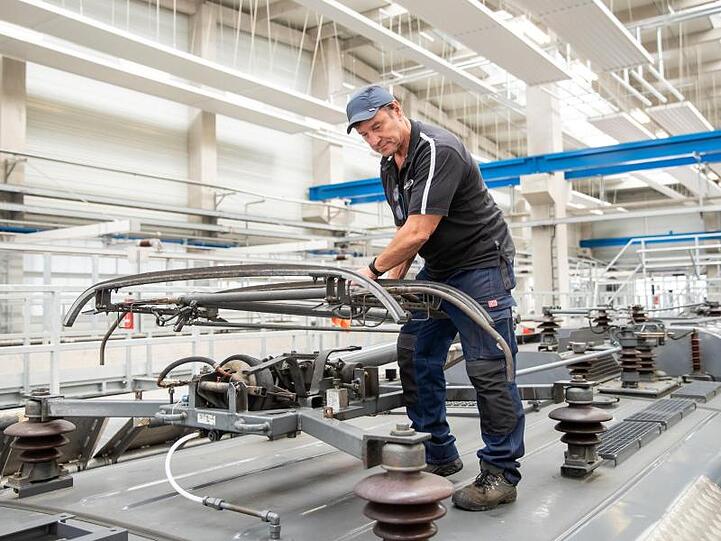 Klaus David, Elektriker in Rente bei der Deutschen Bahn, prüft auf einer Lokomotive im Nürnberger Bahnwerk den Stromabnehmer.