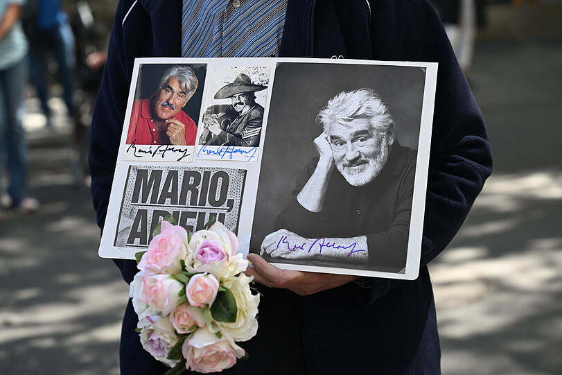 Trauerfeier f&uuml;r Mario Adorf in der Jesuitenkirche Sankt Michael: Ein Gast hat Autogrammkarten der Schauspiel-Legende mitgebracht und auf einem Schild drapiert.