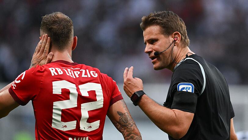 Schiedsrichter Felix Brych (r) spricht mit Leipzigs David Raum, der sich das Ohr hält.