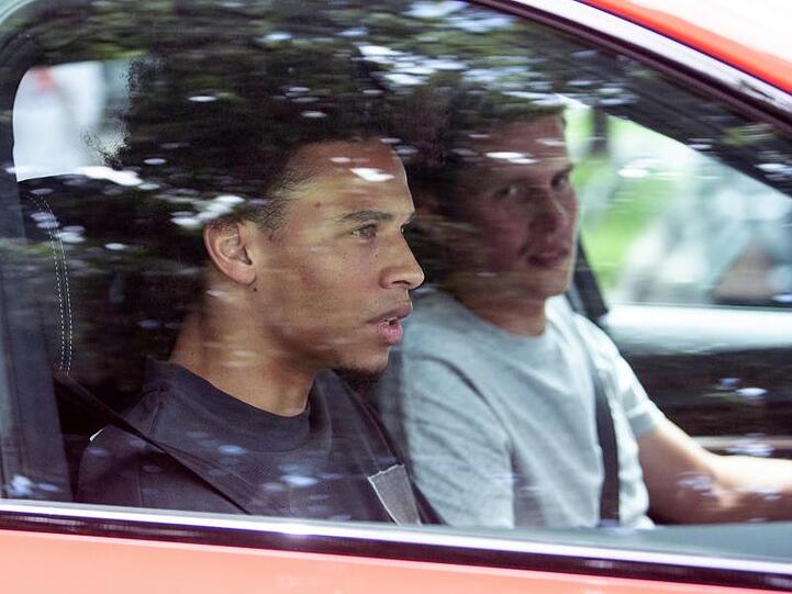 FC Bayern-Neuzugang Leroy Sané (l) sitzt beim Verlassen des Trainingsgeländes des FC Bayern an der Säbener Straße auf dem Beifahrersitz eines Autos. Foto: Matthias Balk/dpa/Archiv