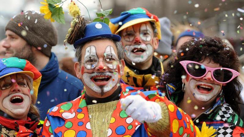 Besucher in Clown-Kostümen werfen in Nürnberg beim Faschingsumzug mit Konfetti.