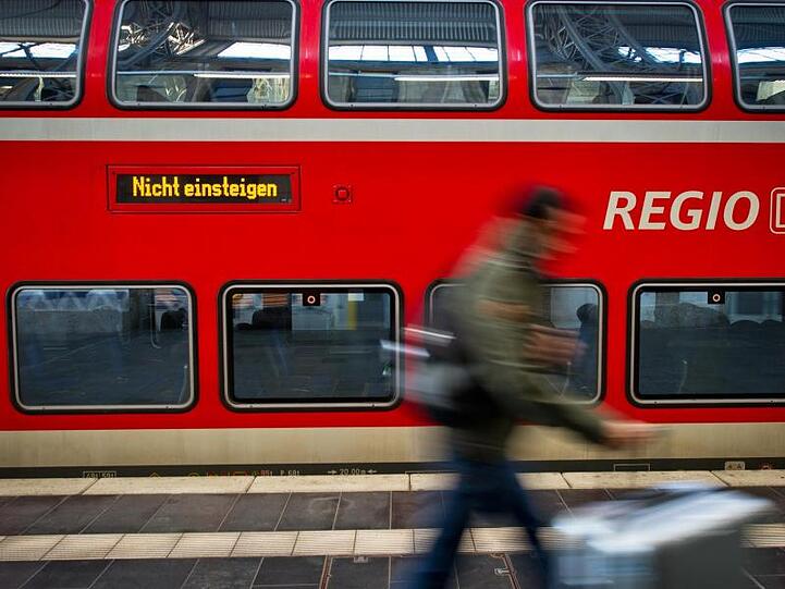 Ein Fahrgast läuft in einem Hauptbahnhof an einer Regionalbahn der Deutschen Bahn vorbei. Foto: Christoph Schmidt/dpa/Archivbild
