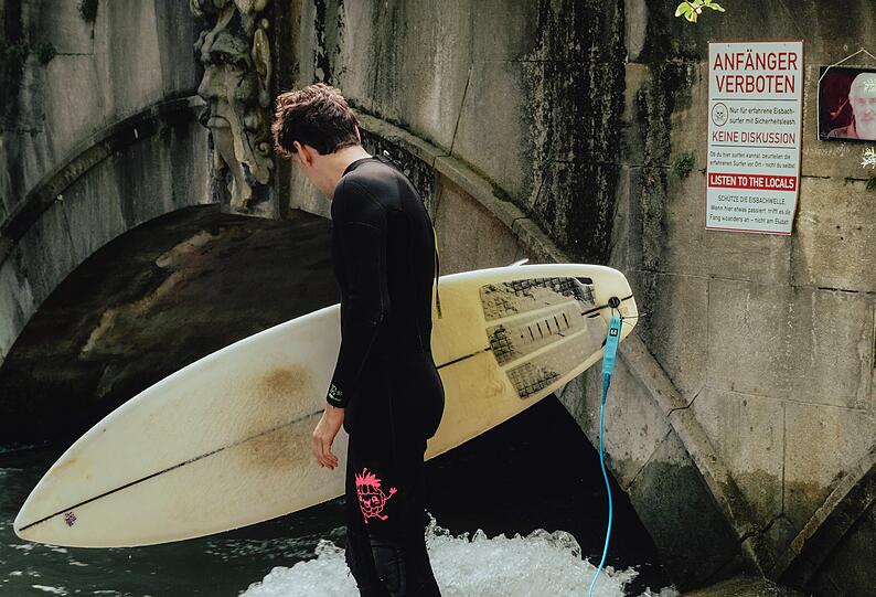 Surfer Paul versteht das Surfverbot nachts nicht. Auf dem Schild rechts hinten wird auf das Surf-Verbot f&uuml;r Anf&auml;nger hingewiesen.