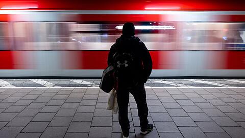 Ein Mann wartet an einer Haltestelle in München auf die S-Bahn.