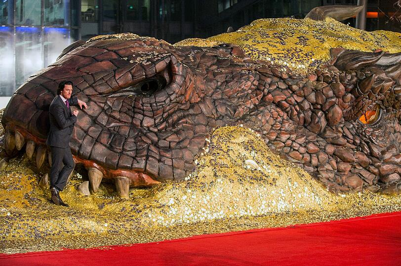 Der britische Schauspieler Luke Evans posiert vor der Europapremiere des Films «Der Hobbit - Smaugs Einöde» an der großen Skulptur des Drachens Smaug.