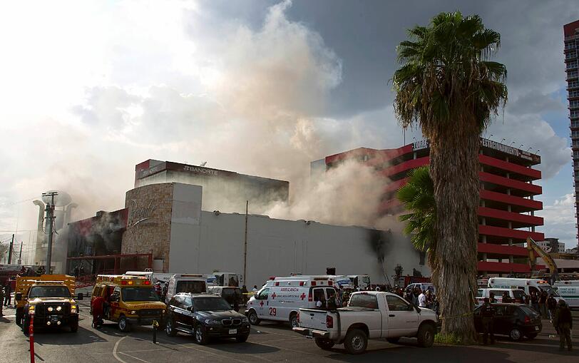 Rettungsfahrzeuge rahmen das Kasino in Monterrey. Noch immer quellen dicke Rauchschwaden in den blauen Himmel.