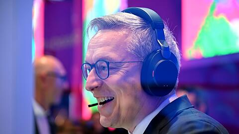 Bundesdigitalminister Karsten Wildberger bei einem Testgespr&auml;ch, bei dem der KI-Assistent eingebunden war. Im Hintergrund steht Telekom-Chef Tim H&ouml;ttges.