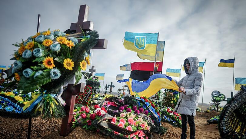 Anna, die Ehefrau eines vor zwei Monaten getöteten Soldaten, stellt auf dem Friedhof der Hafenstadt Odessa die ukrainische Nationalflagge am Grab ihres Ehemannes auf.