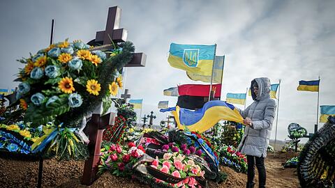 Anna, die Ehefrau eines vor zwei Monaten getöteten Soldaten, stellt auf dem Friedhof der Hafenstadt Odessa die ukrainische Nationalflagge am Grab ihres Ehemannes auf.