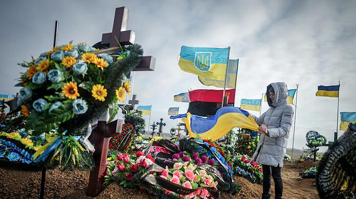 Anna, die Ehefrau eines vor zwei Monaten getöteten Soldaten, stellt auf dem Friedhof der Hafenstadt Odessa die ukrainische Nationalflagge am Grab ihres Ehemannes auf.