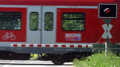 Eine Bahnschranke, an der ein Zug der S-Bahn vorbeifährt. (Symbolbild)