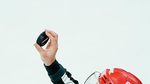 Ein Schiedsrichter hält den Puck in der Hand.